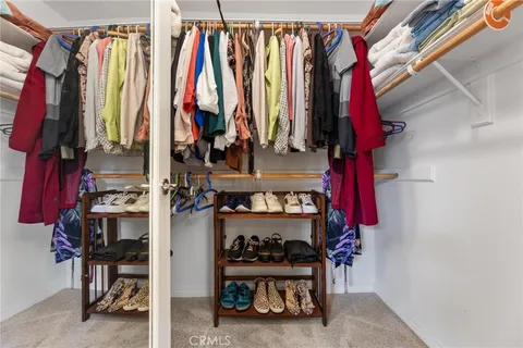 a view of walk in closet with clothes and shoes