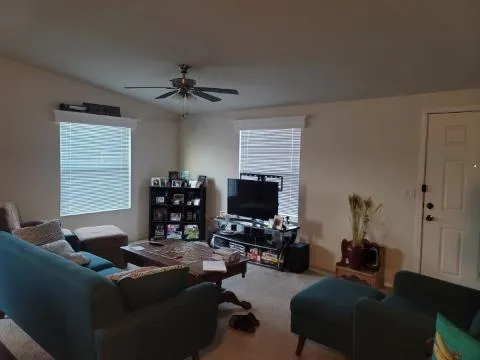 a living room with furniture a ceiling fan and a window