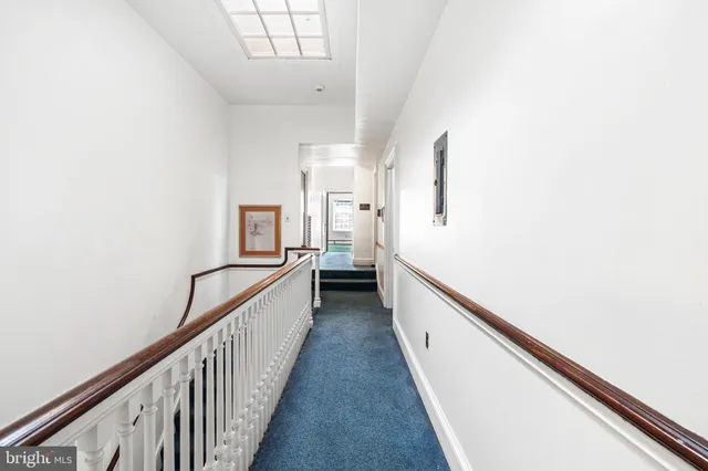 a view of a hallway with white walls and stairs