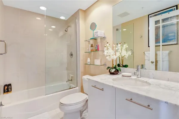 a bathroom with a bathtub shower sink vanity mirror and toilet
