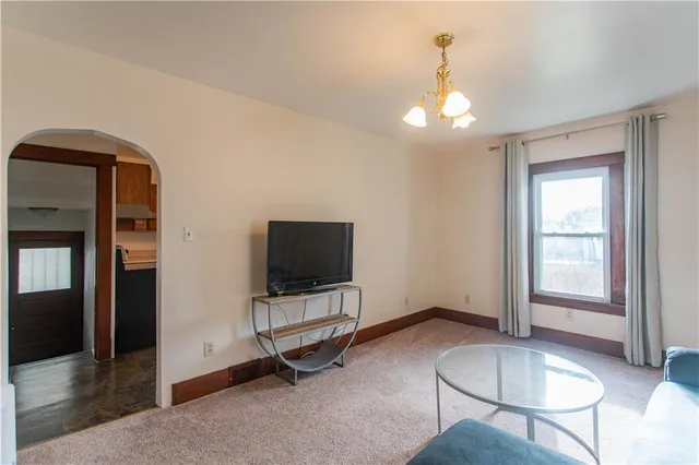 a living room with furniture a flat screen tv and floor to ceiling window