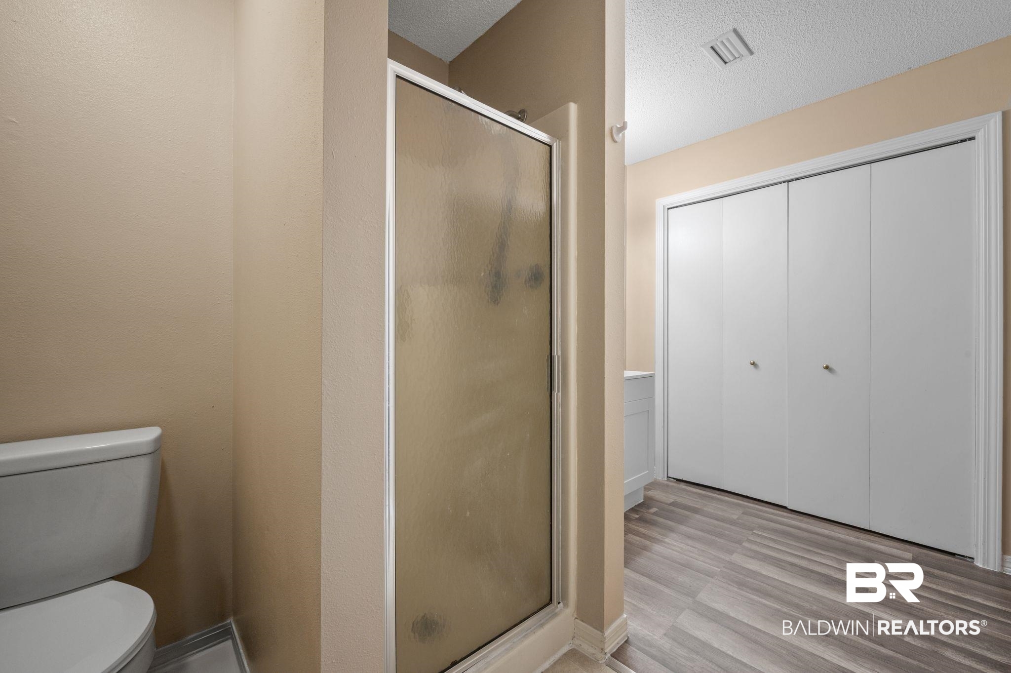 100 Orleans Way Daphne, AL 36526 - Photo 16 of 31 Bathroom featuring hardwood / wood-style floors, a shower with shower door, a textured ceiling, and toilet