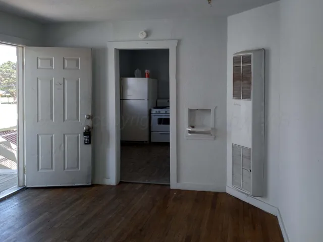 an empty room with wooden floor closet and windows