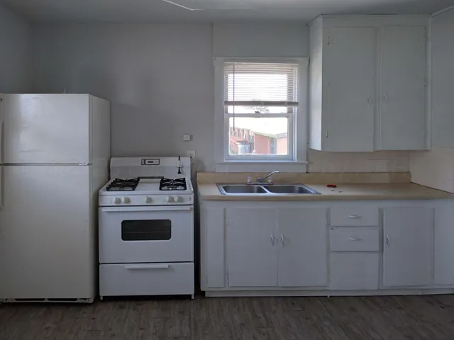 a kitchen with a white stove refrigerator and cabinets