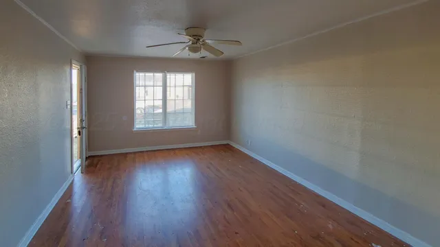 an empty room with wooden floor and windows