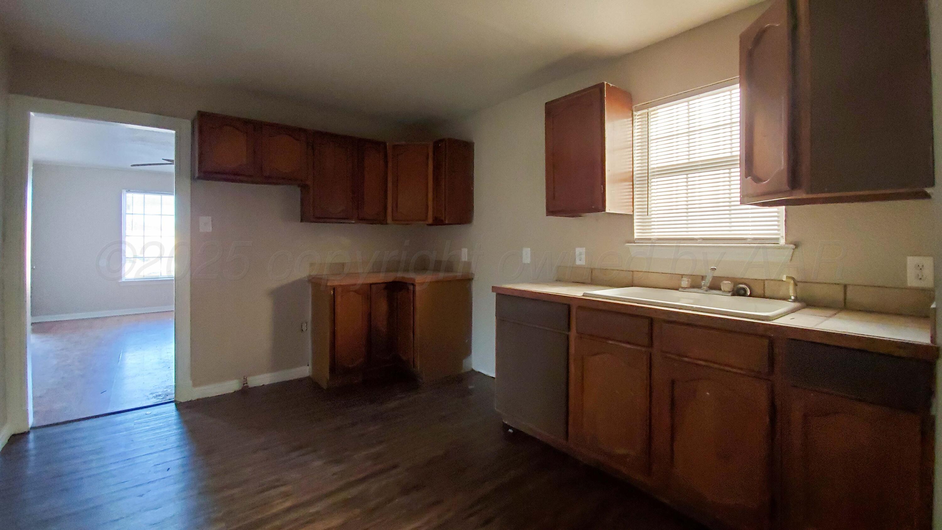 809 South Bryan Street Amarillo, TX 79106 - Photo 7 of 22 a kitchen with stainless steel appliances granite countertop wooden cabinets a sink and dishwasher with wooden floor