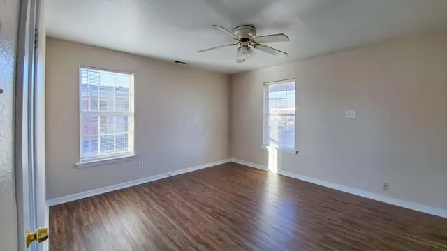 a view of an empty room with a window and wooden floor