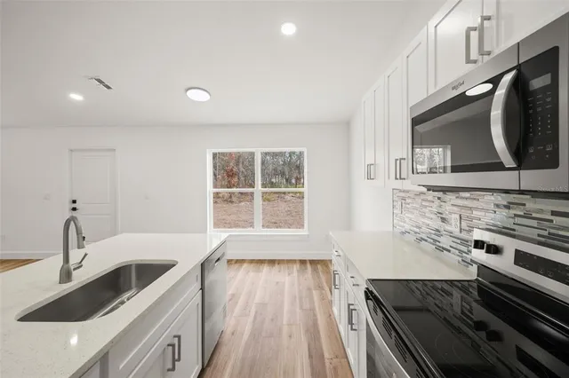 a kitchen with stainless steel appliances a sink a stove a microwave a counter space and cabinets