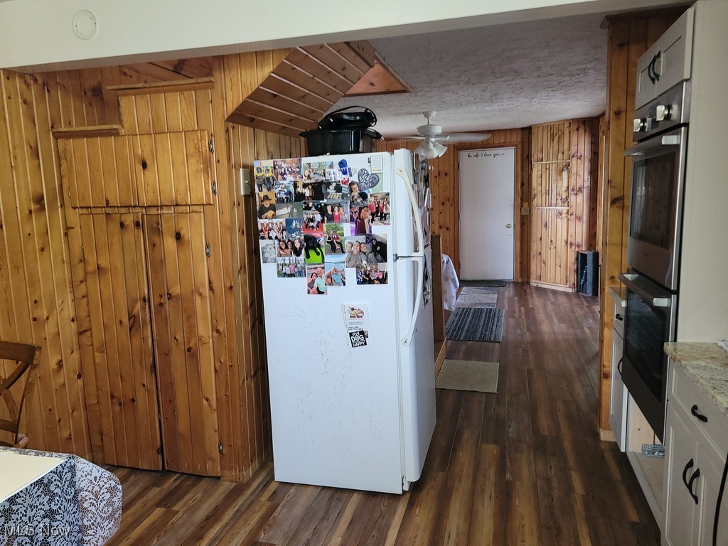 42774 Webster Road Lagrange, OH 44050 - Photo 15 of 37 Kitchen featuring wood walls, freestanding refrigerator, dark wood-style floors, stainless steel double oven, and ceiling fan