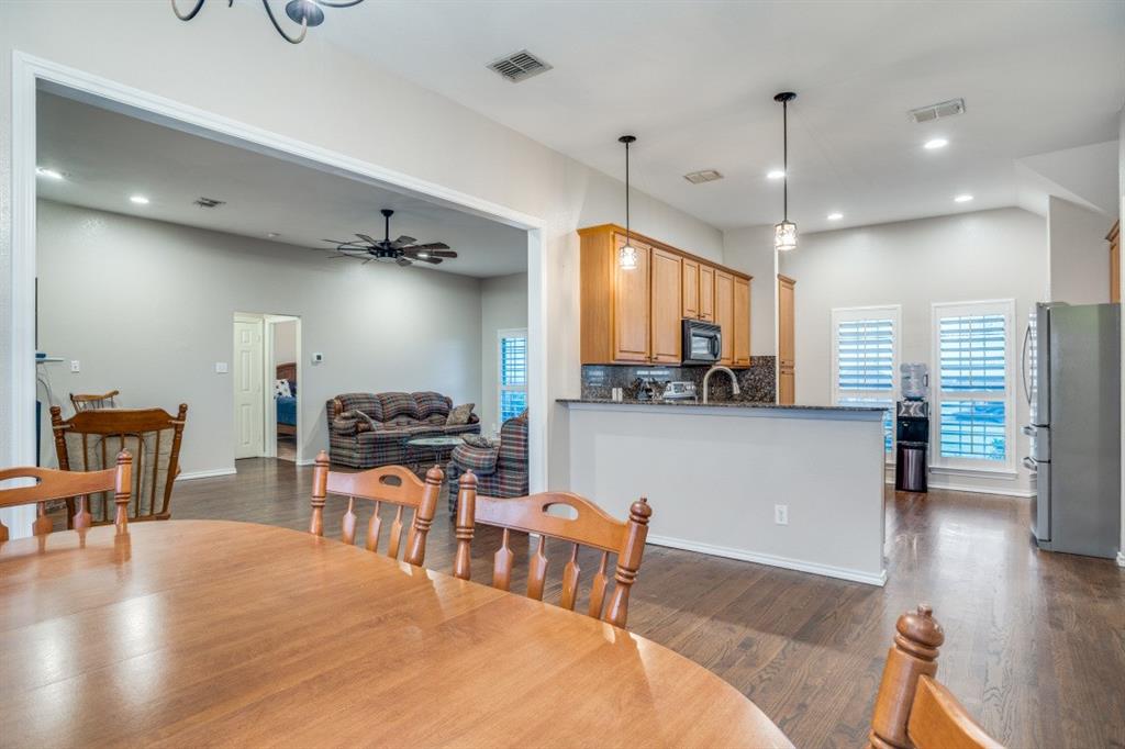 108 High Meadows Court Decatur, TX 76234 - Photo 9 of 29 a kitchen with stainless steel appliances kitchen island granite countertop a stove a refrigerator a sink a dining table and chairs with wooden floor