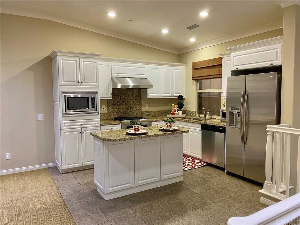 a kitchen with kitchen island stainless steel appliances a sink stove refrigerator and cabinets