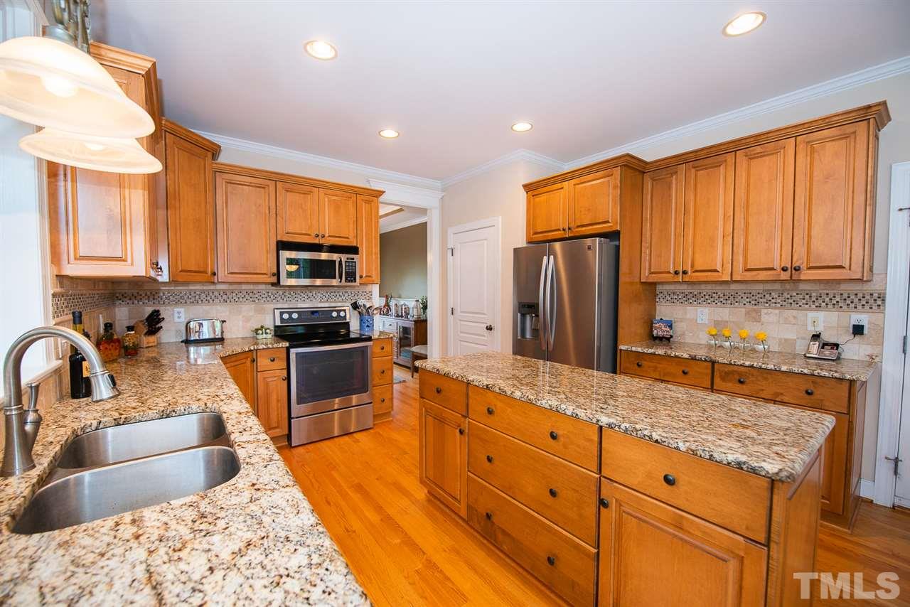 81 Rand Road Raleigh, NC 27603 - Photo 9 of 24 a large kitchen with stainless steel appliances granite countertop a stove a sink dishwasher a refrigerator and wooden cabinets with wooden floor