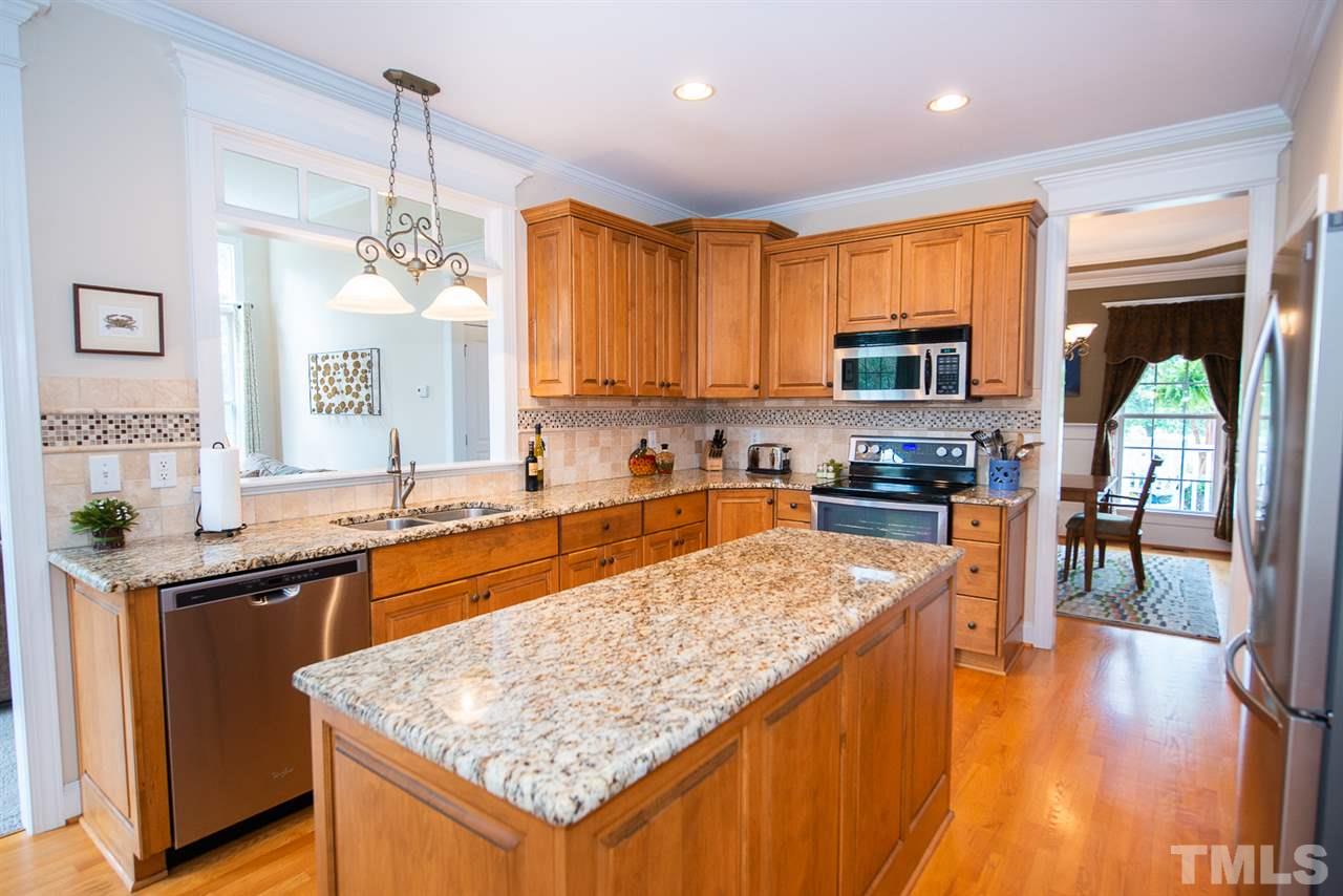 81 Rand Road Raleigh, NC 27603 - Photo 10 of 24 a kitchen with stainless steel appliances granite countertop wooden cabinets a stove top oven a sink and dishwasher with wooden floor