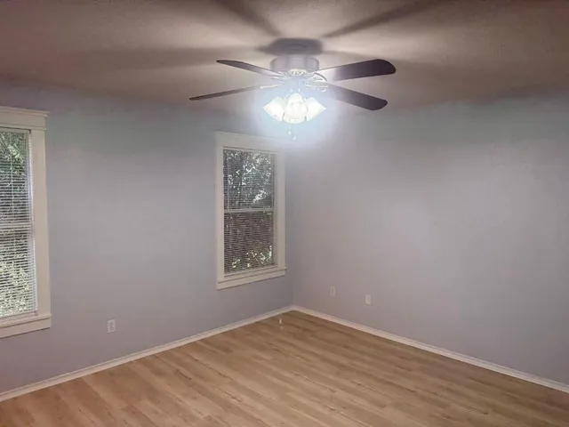 a view of an empty room with a window and wooden floor