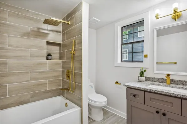 a bathroom with a granite countertop sink a toilet and shower
