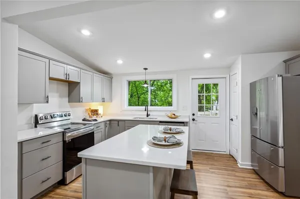 a kitchen with a sink a stove a refrigerator and white cabinets