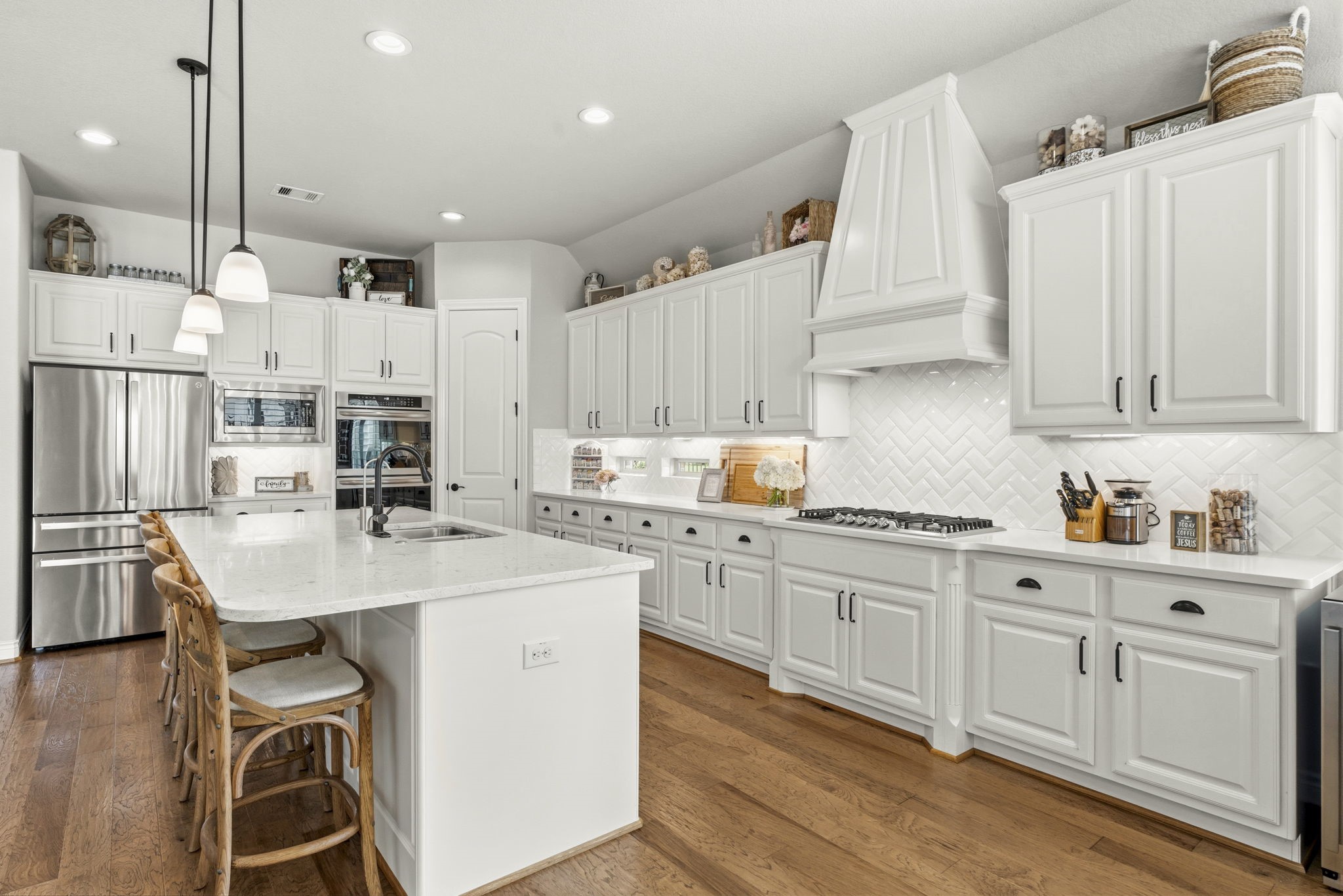 14012 Beartooth Bend Trail Conroe, TX 77384 - Photo 15 of 50 Designed with the serious home chef in mind, the kitchen offers an impressive blend of beauty and functionality. A huge walk-in pantry provides exceptional storage for food, small appliances, and kitchen essentials. Under-cabinet lighting and a herringbone-patterned tile backsplash add the perfect finishing touches to this beautifully appointed space.