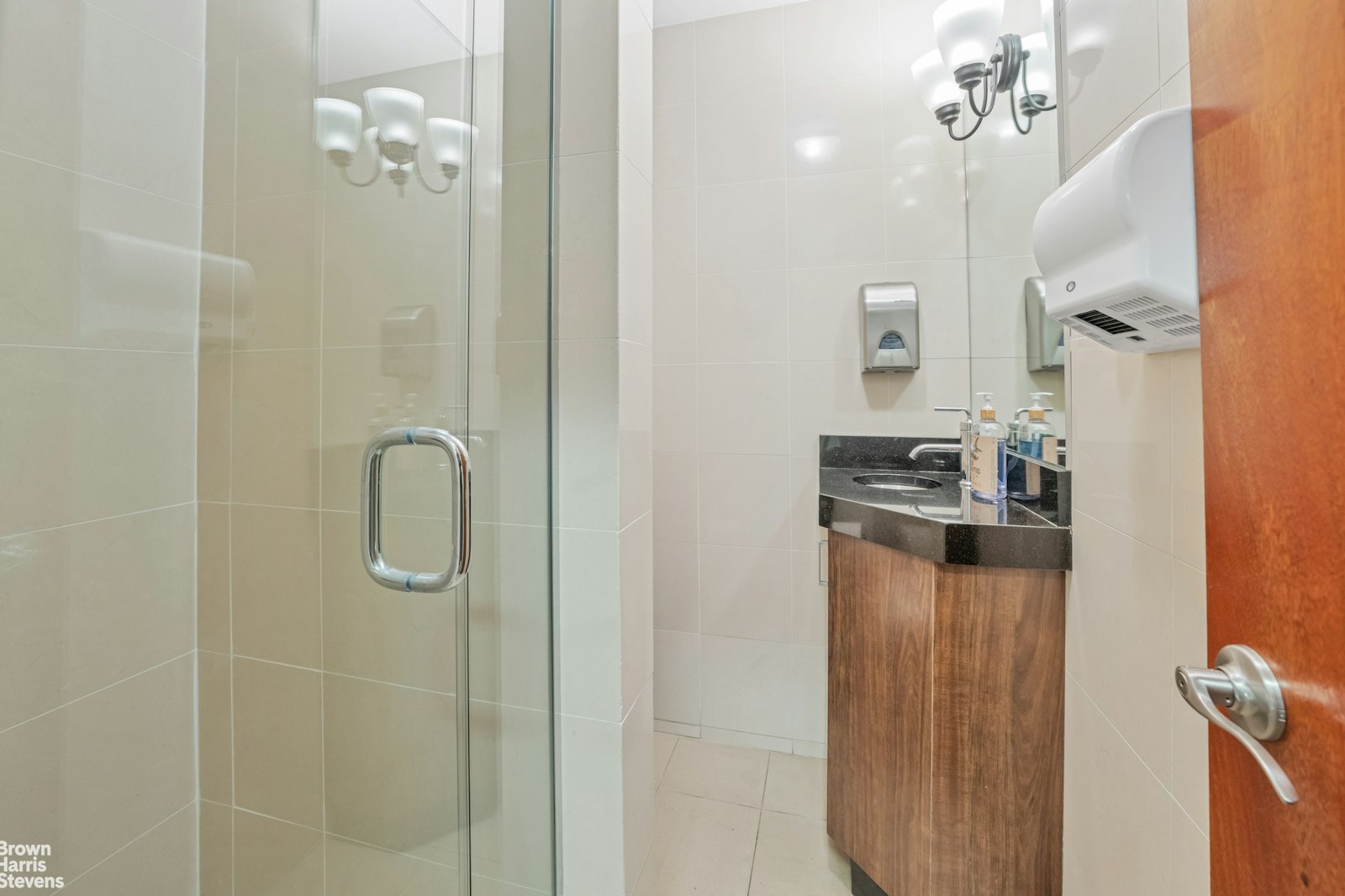 235 East 22nd Street, Unit 1EF Manhattan, NY 10010 - Photo 12 of 15 a bathroom with a granite countertop shower a sink and a mirror
