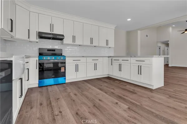 a kitchen with stainless steel appliances granite countertop a stove top oven a sink dishwasher and a refrigerator with wooden floor