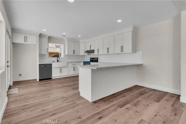 a kitchen with wooden floors and white cabinets