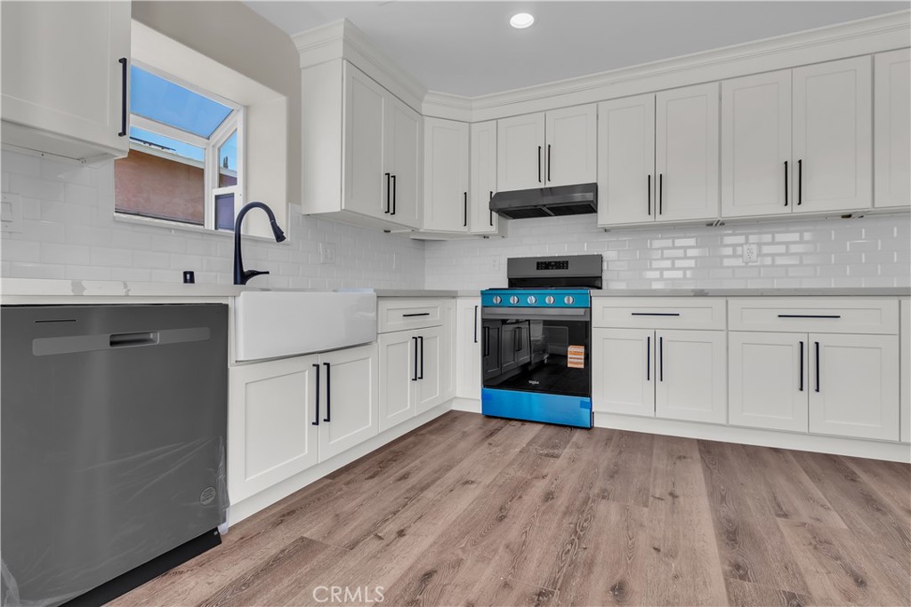 12524 Chanute Street Pacoima, CA 91331 - Photo 14 of 47 a kitchen with stainless steel appliances granite countertop a stove top oven a sink and white cabinets