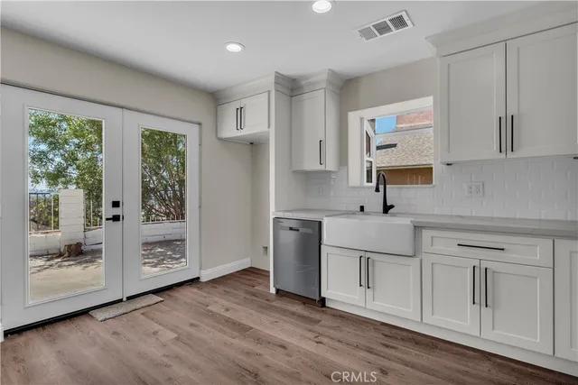 a kitchen with white cabinets and wooden floors