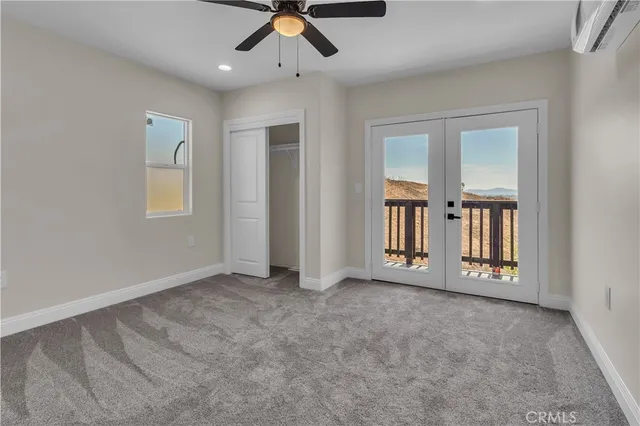 an empty room with chandelier fan and windows