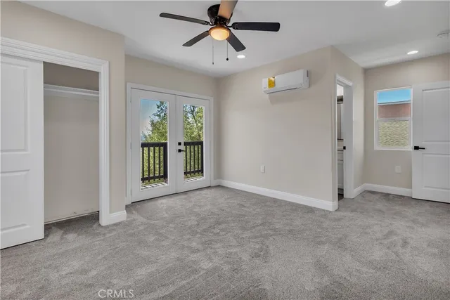 an empty room with chandelier fan and windows