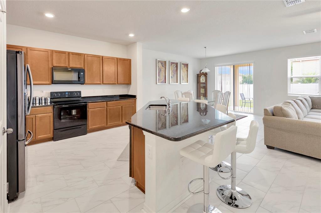 11530 Brighton Knoll Loop Riverview, FL 33579 - Photo 12 of 64 a kitchen with stainless steel appliances granite countertop a sink and stove top oven with wooden floor
