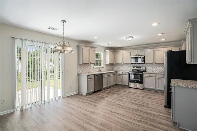 a large kitchen with a center island wooden floor stainless steel appliances and cabinets