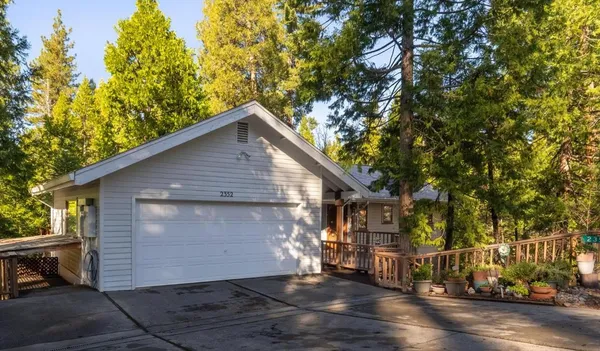 a view of a house with a large tree and wooden fence