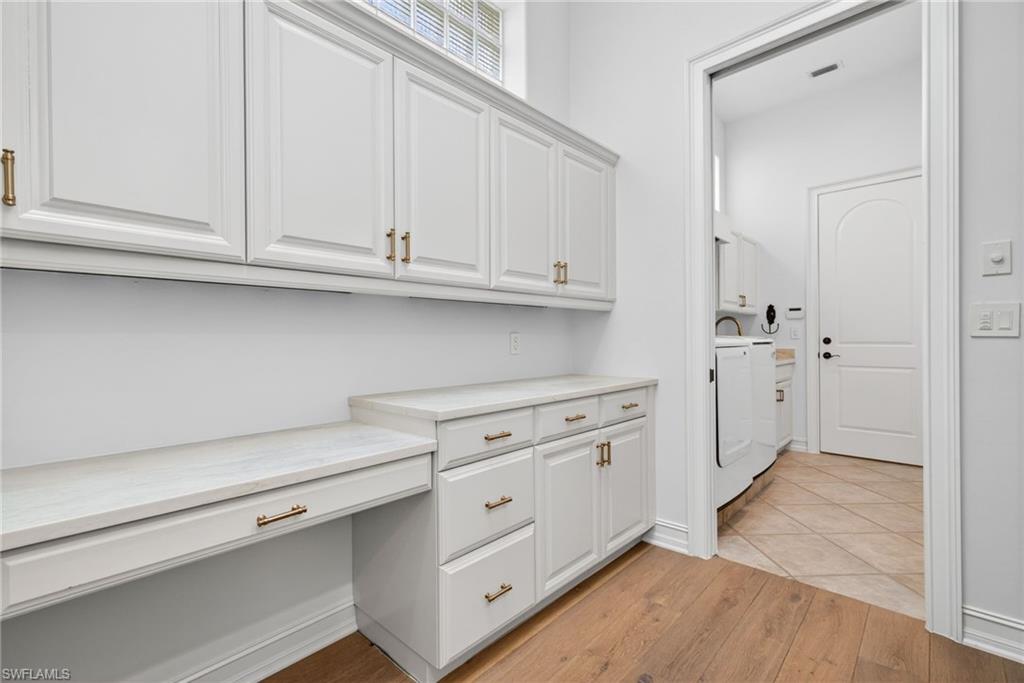 3296 Lookout Lane Naples, FL 34112 - Photo 25 of 39 a kitchen with white cabinets and a stove with wooden floor