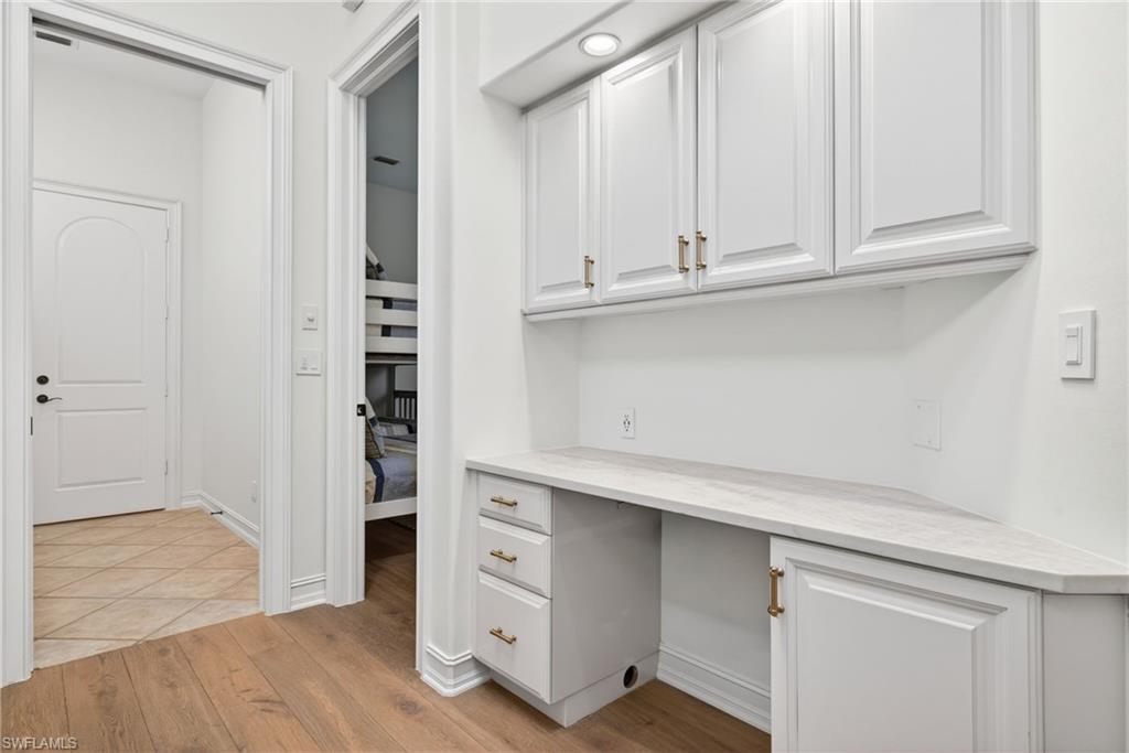 3296 Lookout Lane Naples, FL 34112 - Photo 26 of 39 a kitchen with white cabinets and a wooden floor