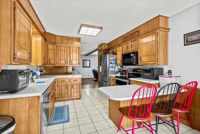 a kitchen with stainless steel appliances granite countertop a refrigerator a stove top oven a sink dishwasher and a refrigerator with wooden floor