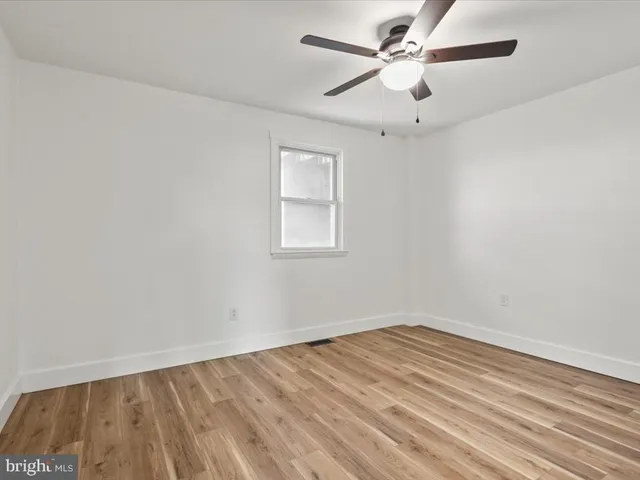 an empty room with a window and a ceiling fan