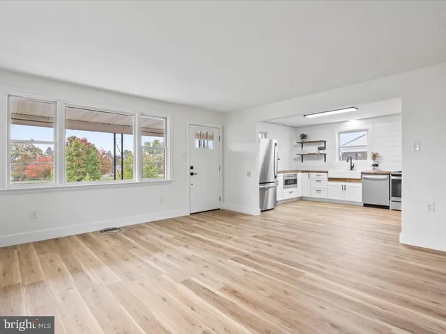 a view of empty room with wooden floor and kitchen view