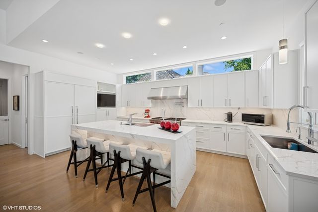 a kitchen with a sink a stove a refrigerator and white cabinets with wooden floor