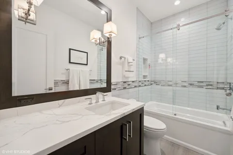 a bathroom with a granite countertop sink a toilet a mirror a vanity and bathtub
