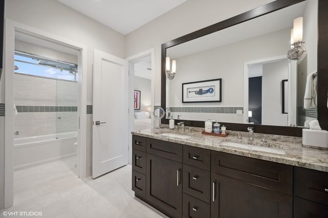 a bathroom with a granite countertop double vanity sink a mirror and a bathtub