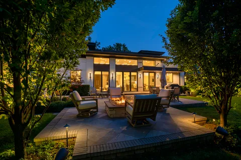 a view of a patio with couches table and chairs and potted plants with large tree