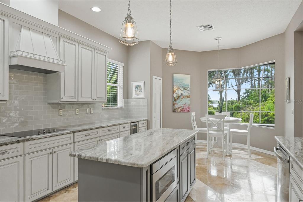 9103 Creedmoor Lane New Port Richey, FL 34654 - Photo 24 of 90 a kitchen with granite countertop a stove center island a large window cabinets and stainless steel appliances