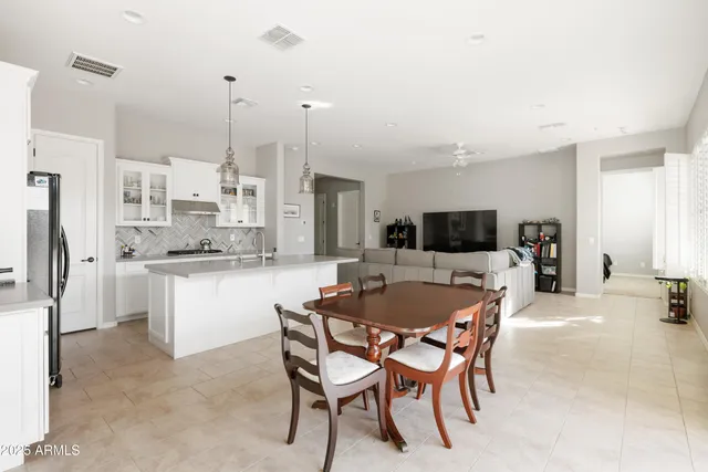 a kitchen with kitchen island a dining table chairs and white cabinets
