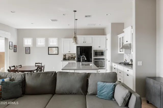 a large living room with stainless steel appliances kitchen island granite countertop a couch a fireplace and a dining table with wooden floor