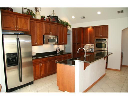 Kitchen. This elegant functional kitchen is an entertainers dream. Rich cherry cabinetry, the granite counter tops, island, double oven radiant cooktop stove and pull out drawers provide all you need for parties. Under cabinet lighting showcases the kitchen.