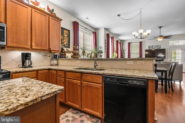 a kitchen with stainless steel appliances granite countertop wooden cabinets a stove a sink a dining table and chairs