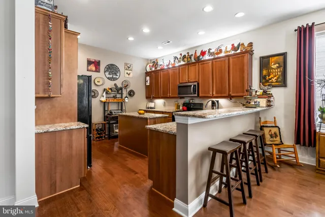 a kitchen with stainless steel appliances granite countertop a stove top oven a refrigerator and a dining table with wooden floor