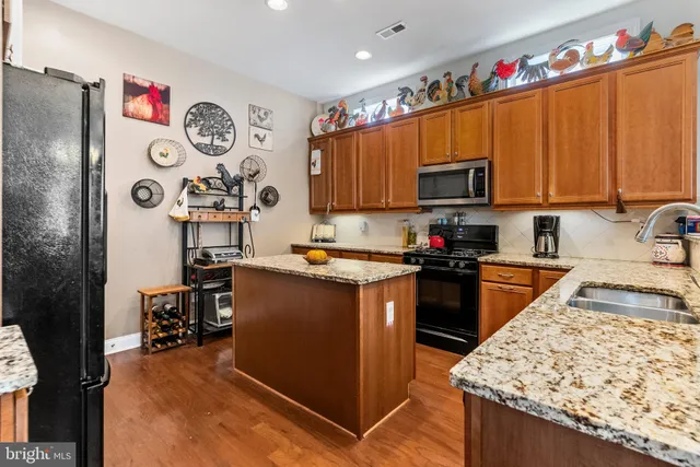 a kitchen with stainless steel appliances granite countertop a refrigerator stove top oven and sink