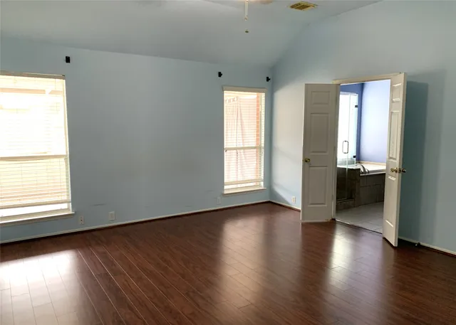 an empty room with wooden floor and windows