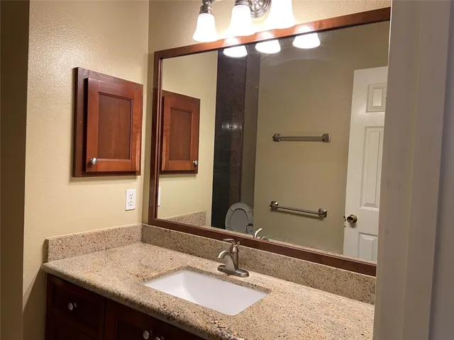 a bathroom with a granite countertop sink and a mirror