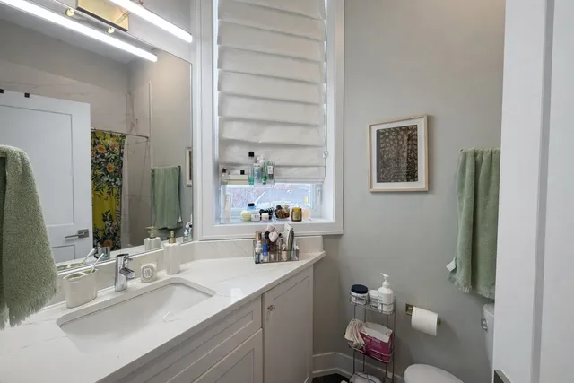 a bathroom with a sink vanity mirror and toilet